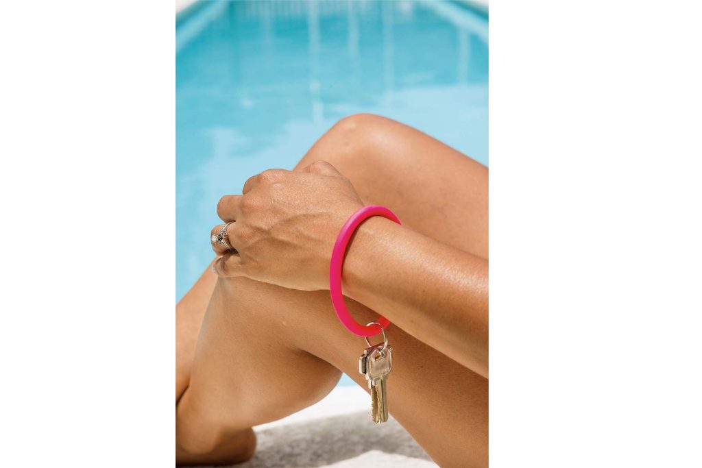 A woman wearing the RINGZ key ring on her wrist at the pool.